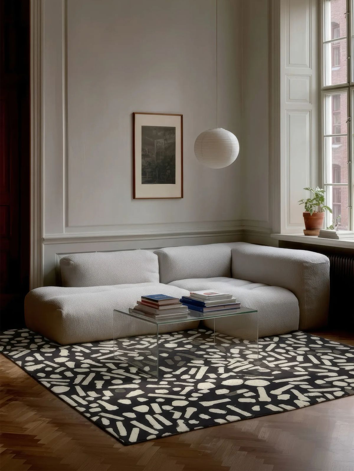 Black rug scattered with cream confetti shapes beneath a bouclé sofa and paper pendant lamp