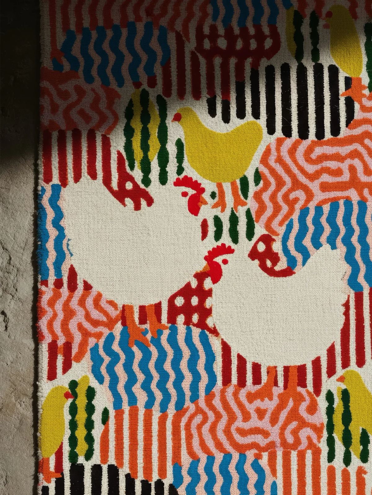 Close-up of a tufted rug with white hens, yellow chicks and wavy red, blue and orange stripes
