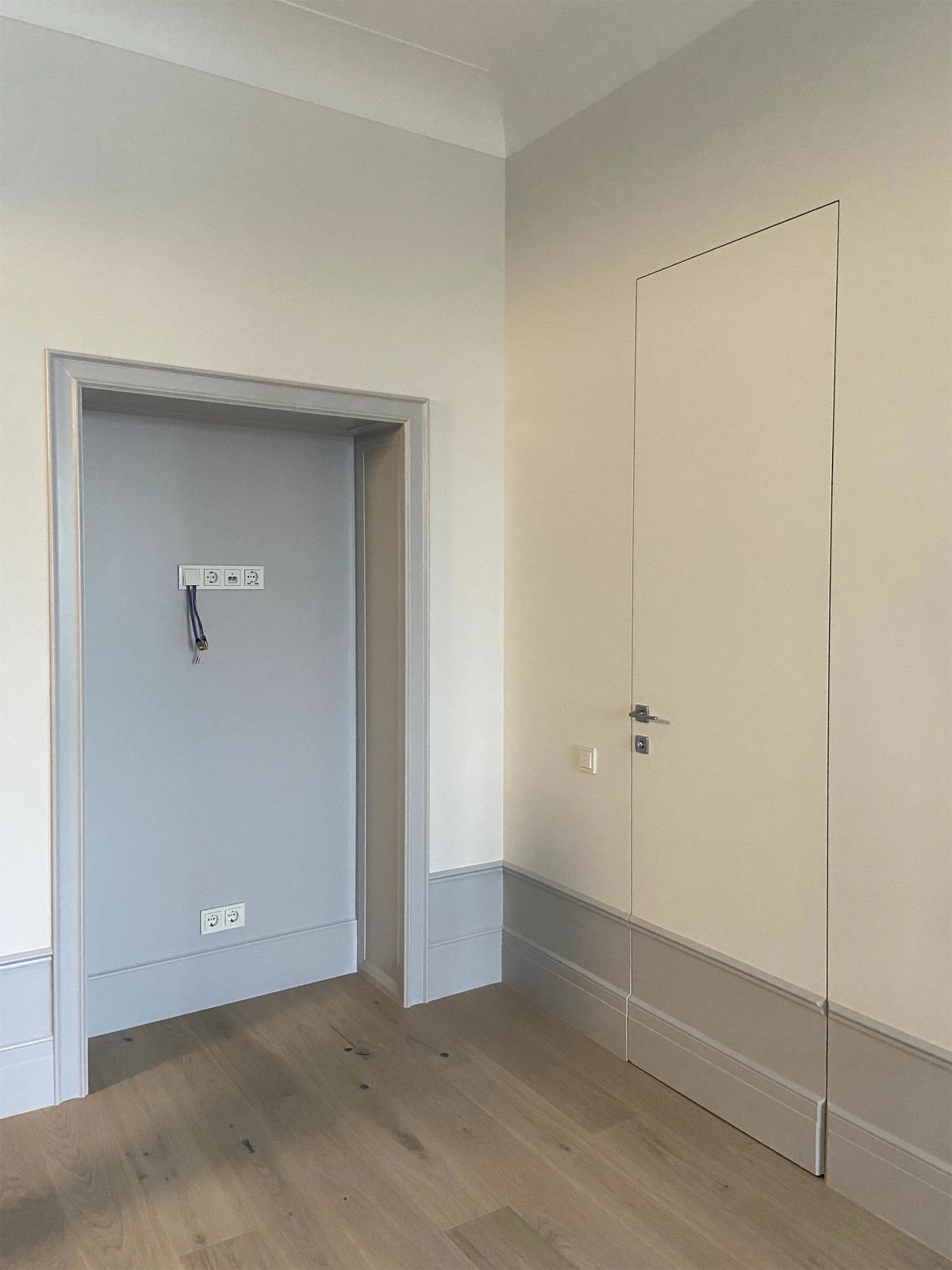 Finished walls before furnishing, with a grey-painted niche, flush hidden door and grey skirting