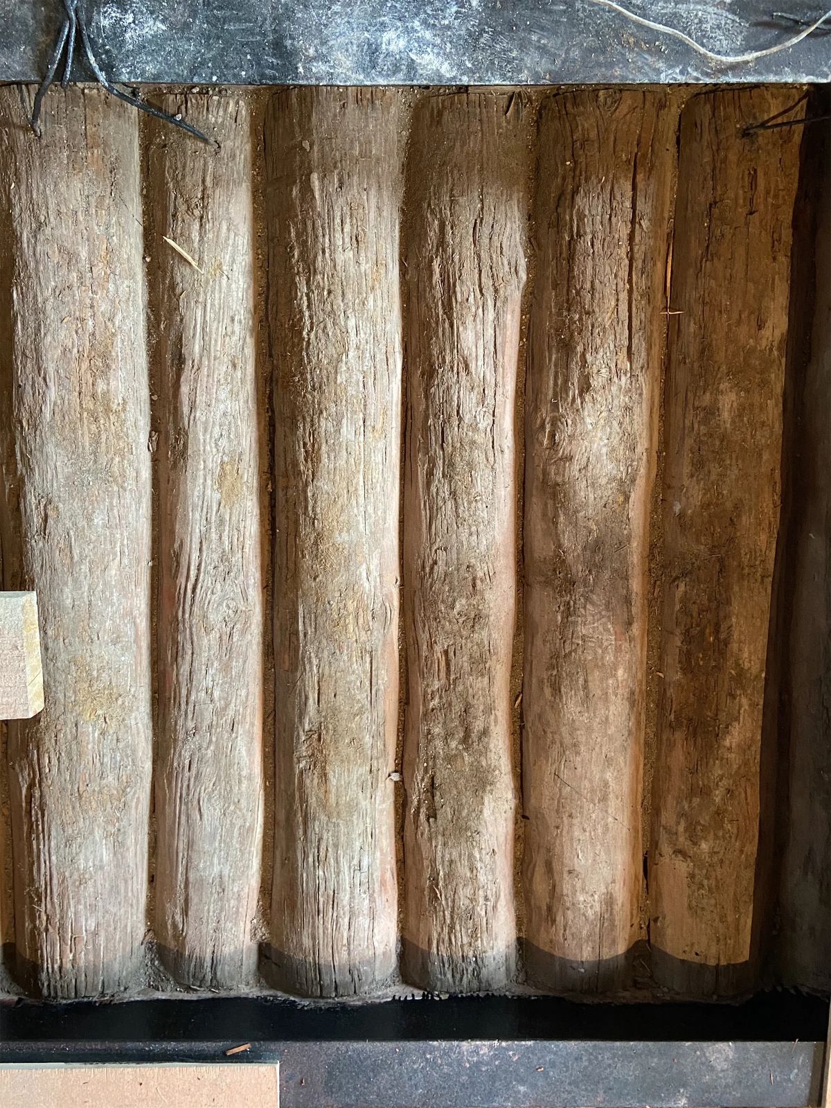 Close-up of old round timber logs uncovered inside a wall during the renovation