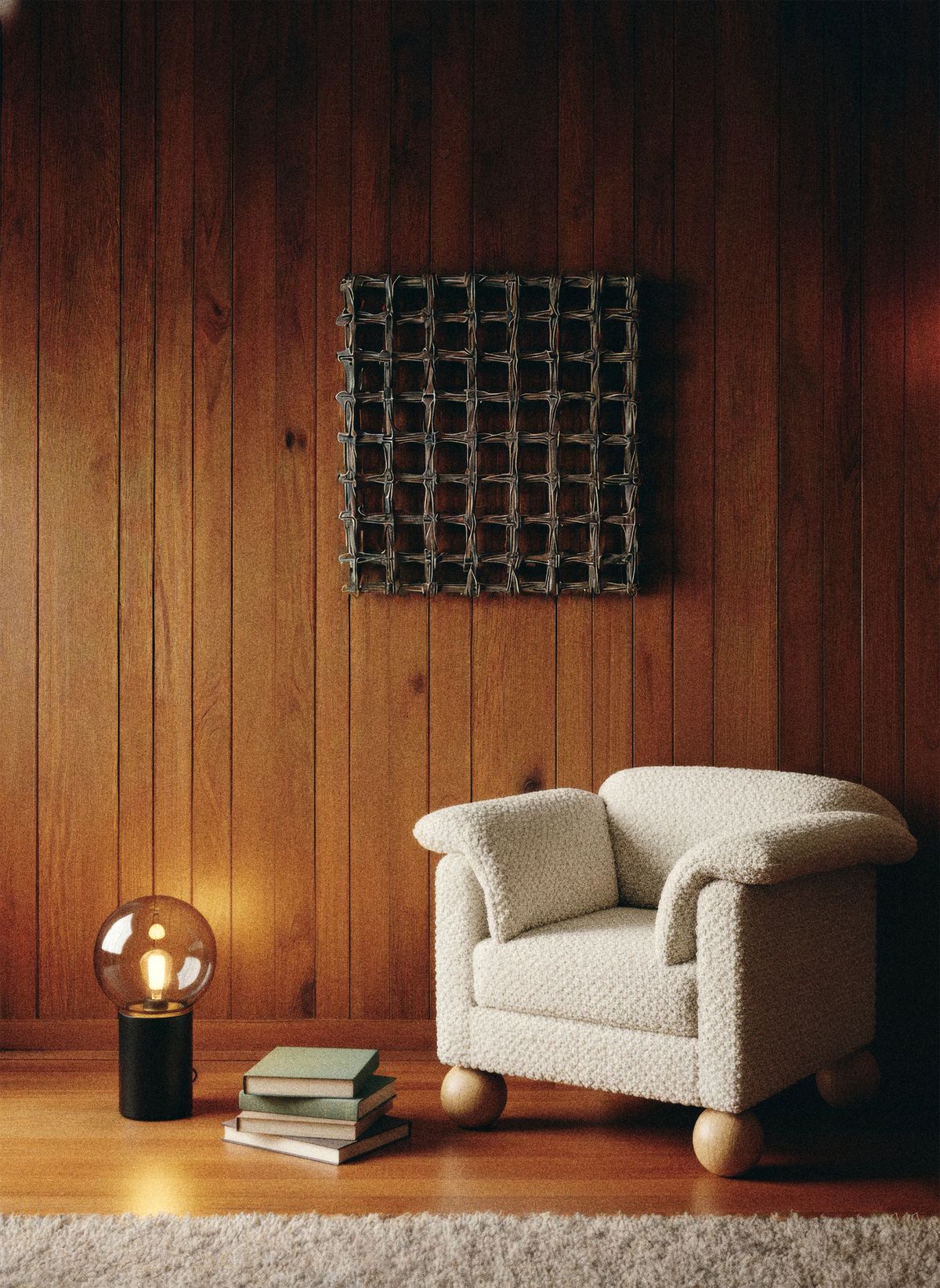 Cream bouclé armchair on wooden ball feet in a wood-panelled room with a globe lamp and books