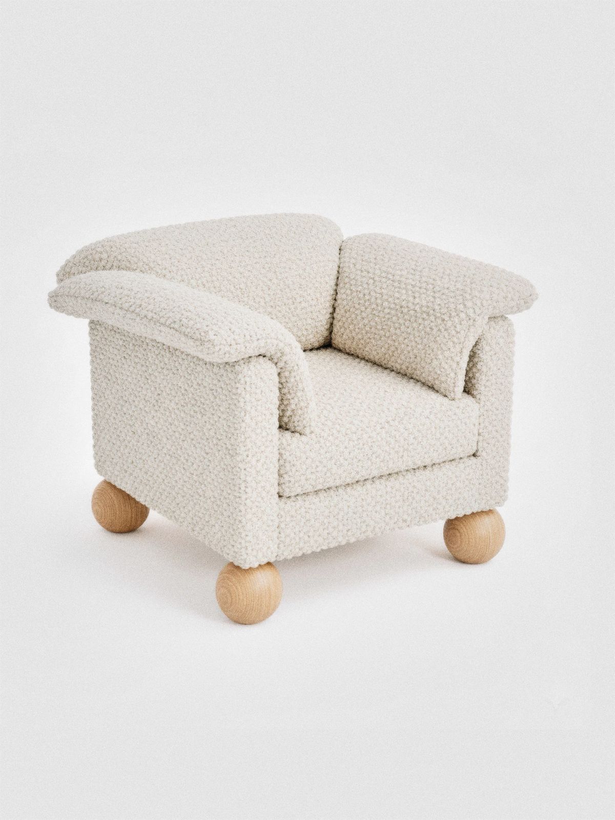 Chunky armchair in cream knotted upholstery with soft rolled arms on four natural wood ball feet