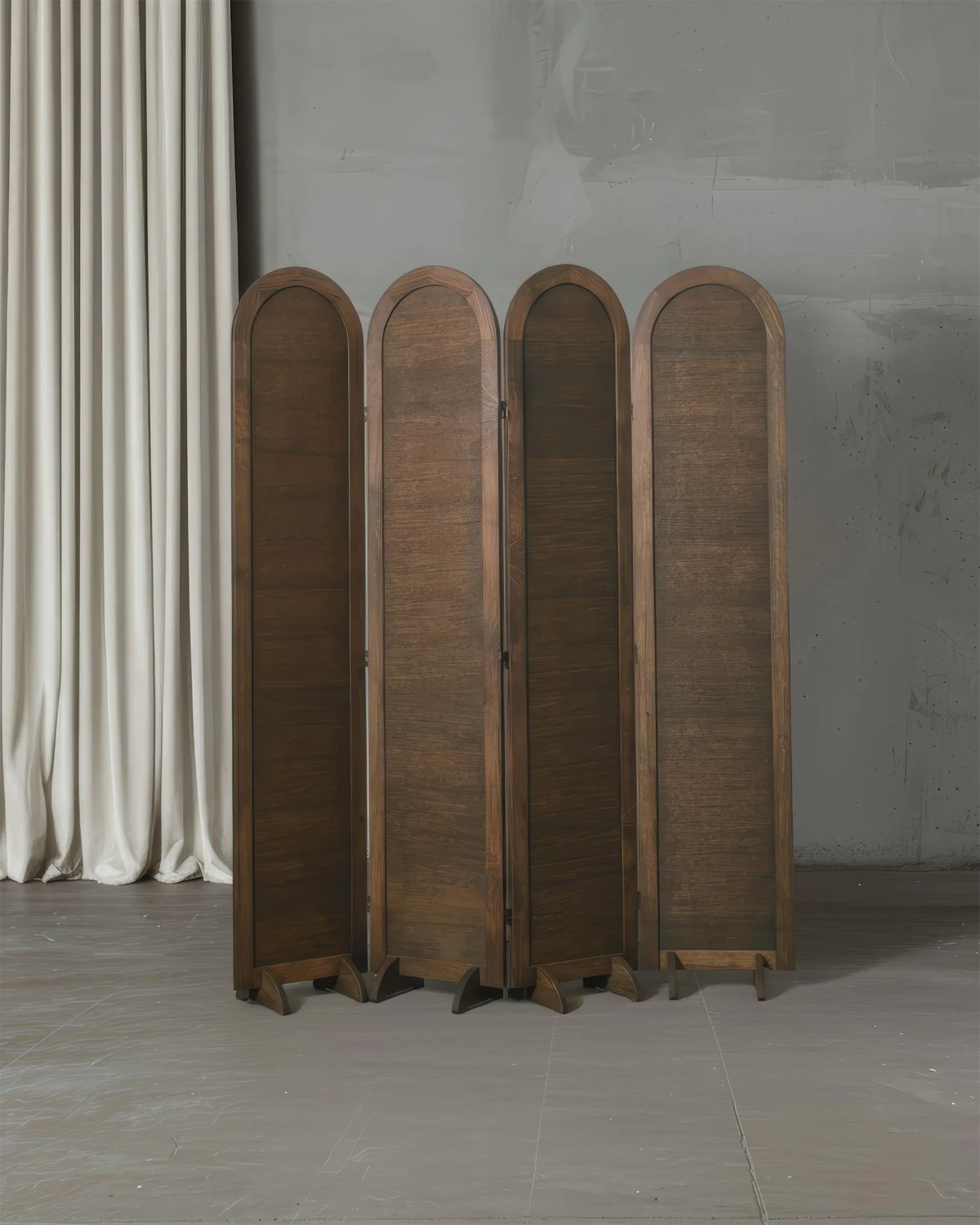 Four tall arched panels in dark brown wood and cane beside a linen curtain on a grey floor