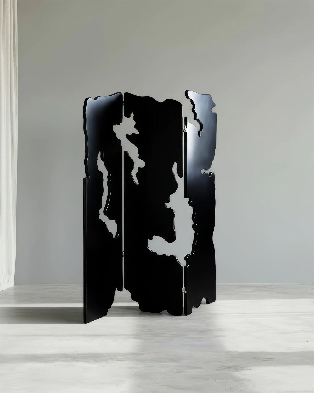 Sculptural black screen with jagged, irregular cut-out edges in a pale grey empty room