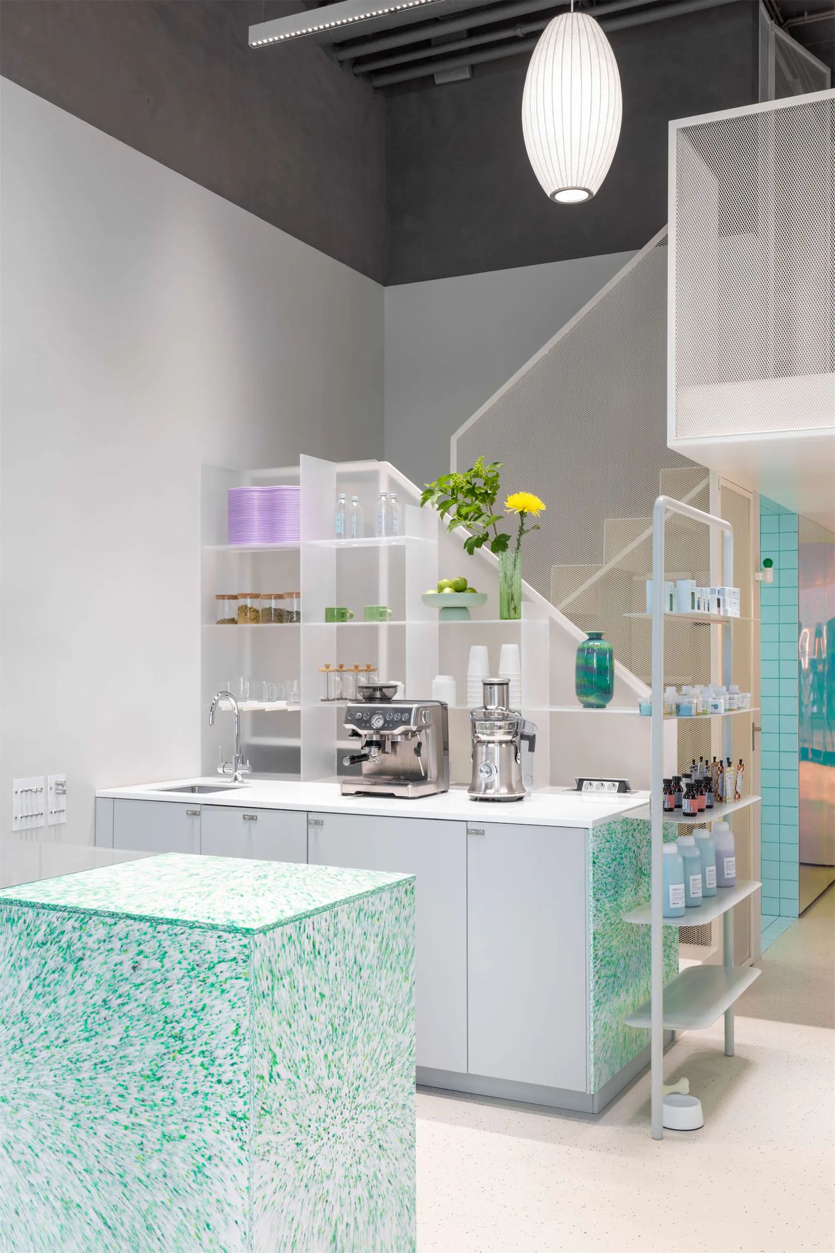 Salon bar with white shelving under the staircase, espresso machine and a green speckled reception block