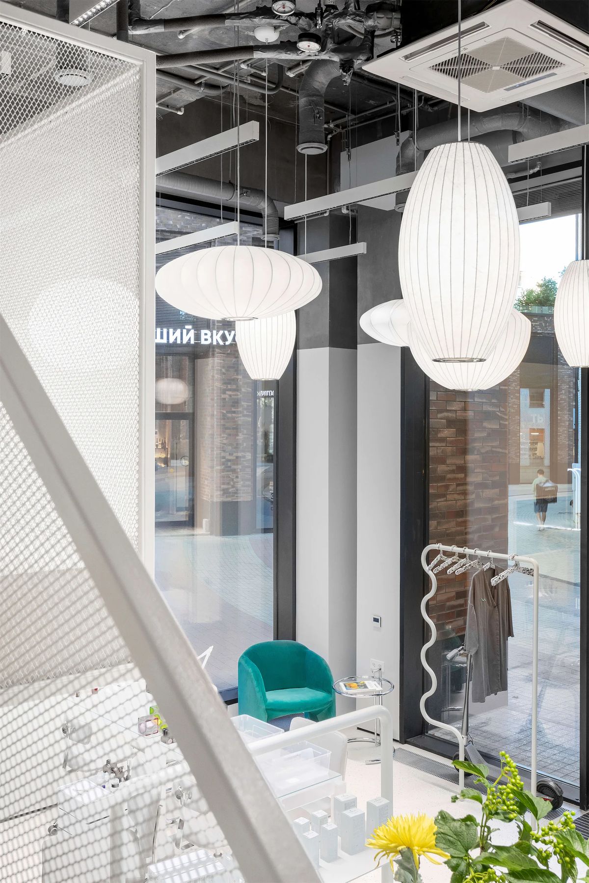 View from the mesh staircase over a teal armchair, paper lanterns and a wavy clothes rail