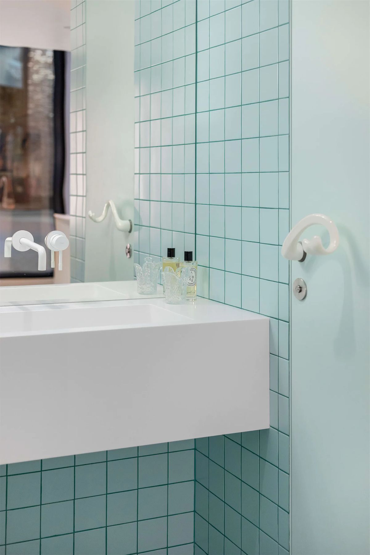 Washroom with mint square tiles, white floating basin and sculptural white hook and taps