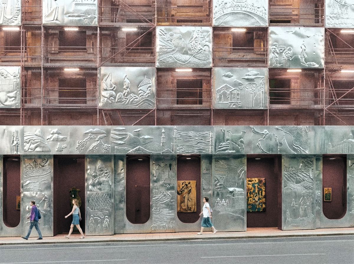 Embossed aluminium relief panels on scaffolding over a Moscow building, with arched niches at street level