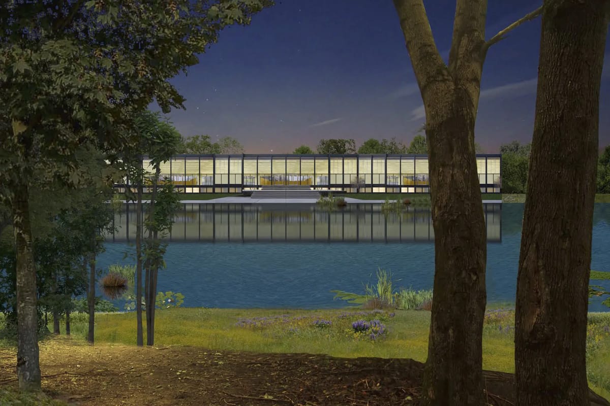 Night render of a long glazed pavilion reflected in a lake, framed by tree trunks