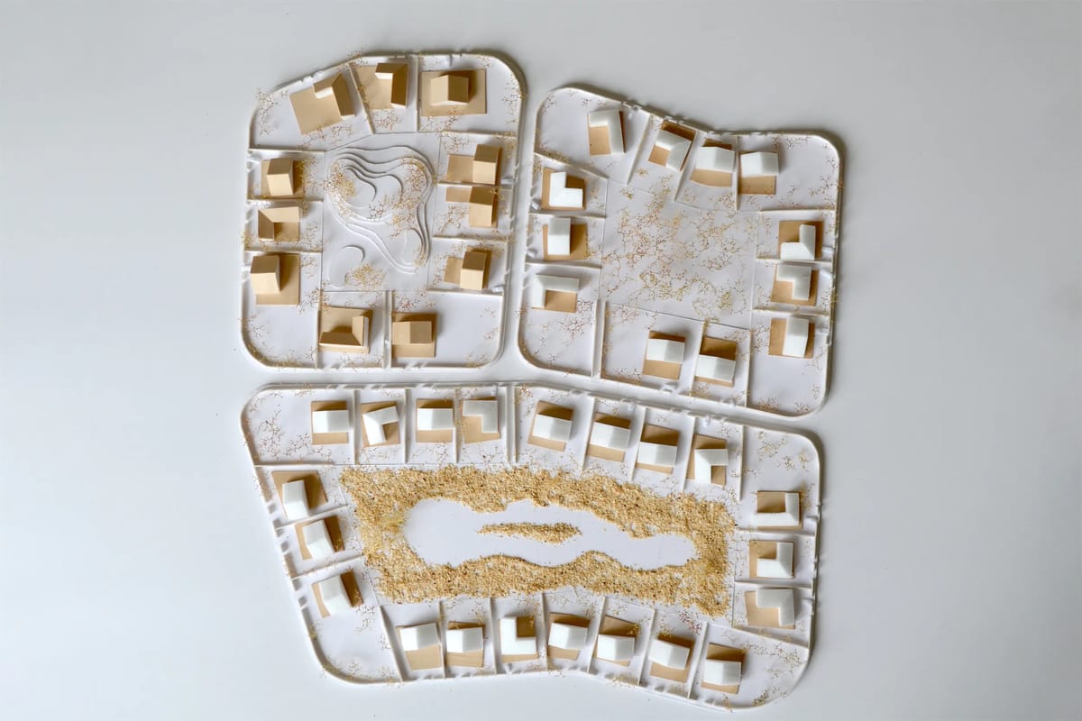 Site model with white and wooden house blocks around a central green and a contoured hill