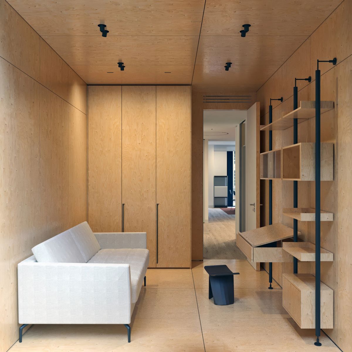 Plywood-lined study with a white sofa, tall wardrobe and pole-mounted shelving with a fold-down desk