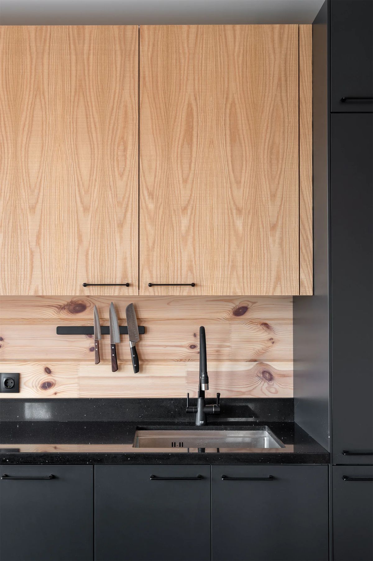 Kitchen sink wall with knives on a magnetic strip against a knotty pine backsplash
