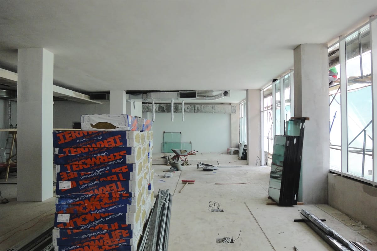 Stripped-out interior under construction with stacked insulation packs, columns and new window glazing