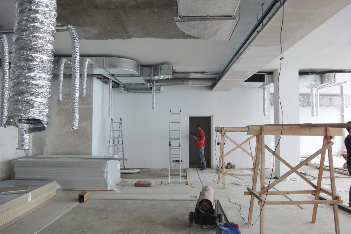 Space under construction with foil ventilation ducts, ladders, wooden trestles and a heater