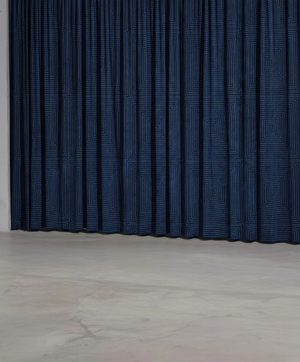 Close render of a pleated navy curtain with a woven square spiral pattern above a concrete floor